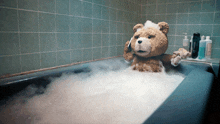 a teddy bear is taking a bath in a tub