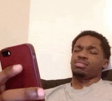 a man is making a funny face while looking at his cell phone .
