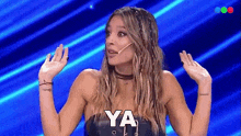 a woman with a microphone in her mouth says ya on a blue background