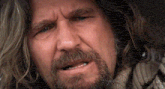 a man with long hair and a beard is making a sad face