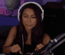 a woman wearing headphones is sitting at a desk in front of a microphone .