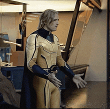 a man in a yellow and blue superhero suit is standing in a room