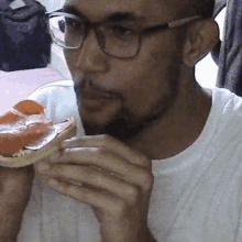 a man wearing glasses is eating a pizza