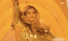 a woman in a gold dress is dancing in front of a yellow background