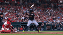 a baseball player swings his bat at a pitch while a catcher watches