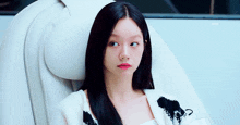 a woman with long black hair is sitting in a white chair looking up .
