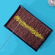 a person cutting a chocolate cake with pistachios on it