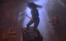 a person is jumping off a box in a dark room with chairs in the background