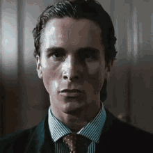 a man in a suit and tie looks at the camera with a serious look on his face