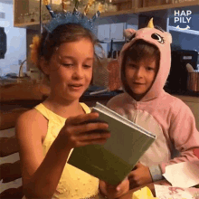 a boy in a unicorn costume looks at a book while a girl looks at it
