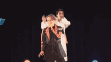 a man singing into a microphone while another man dances behind him