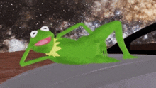 kermit the frog is laying on the hood of a car in space .