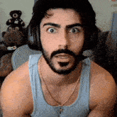 a man with a beard is wearing headphones and a tank top