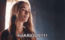 a woman is standing in front of a window and saying hilarious !