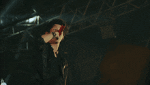 a man singing into a microphone with the letter d visible behind him