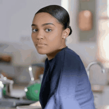 a woman in a blue shirt is sitting in a kitchen