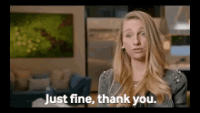 a woman is standing in a living room and saying `` just fine , thank you . ''