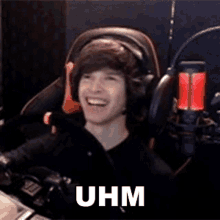 a man wearing headphones is sitting in a chair in front of a microphone and smiling .