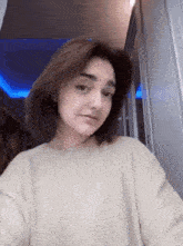 a woman is taking a selfie in a room with a blue light on the ceiling .