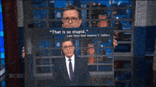 a man in a suit and tie holds a sign that says " that is so stupid "