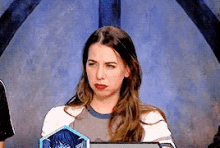a woman sitting in front of a blue wall with a shield on it