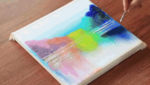 a person is painting a landscape on a canvas with a brush