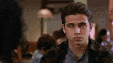 a man in a plaid shirt is making a funny face while looking at another man in a restaurant .