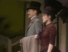 a man in a top hat and a woman in a dress are standing next to each other on a stage .