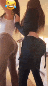 two women are standing next to each other and one of them has a smiley face on her face .
