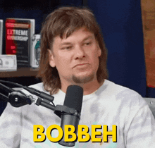a man is sitting in front of a microphone and the word bobbeh is on his shirt