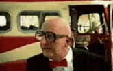 a bald man with glasses and a red bow tie