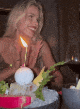 a woman is sitting at a table with a candle lit up