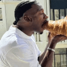 a man is eating a croissant with his mouth .