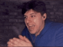 a man wearing headphones and a blue hoodie is making a funny face .