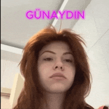 a woman with red hair is standing in front of a sign that says ' günaydin '