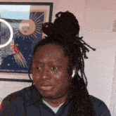 a man with dreadlocks is sitting in front of a framed picture of a sun