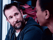 a man with a beard and a stethoscope around his neck is talking to a woman