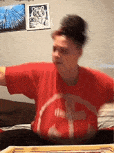 a man in a red shirt with the letter t on it throws a ball
