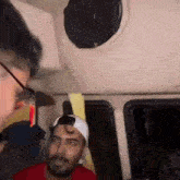 a man wearing glasses and a hat is sitting in a car with a speaker on the ceiling .