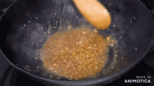 a wooden spoon is stirring a brown sauce in a pan .