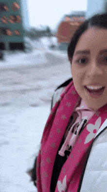 a woman wearing a pink louis vuitton scarf and a white jacket