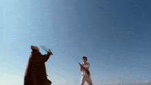 a man in a white suit and a man in a red cape are fighting with swords
