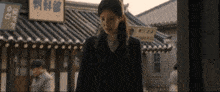 a woman stands in front of a building with chinese writing