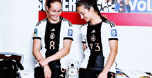 two female athletes wearing black and white jerseys with the number 8 and 13 on them