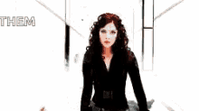 a woman in a black suit is standing in a hallway with a man in a black suit behind her .