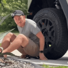 a man is kneeling on the ground next to a tire that says goodyear