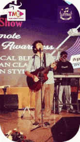 a man singing into a microphone in front of a sign that says tm3 show