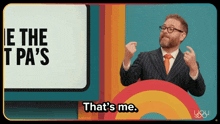 a man in a suit says that 's me in front of a rainbow