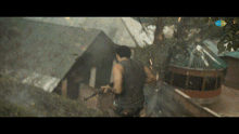 a man in a black tank top is holding a sword in front of a house