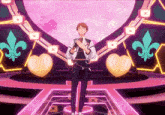 a man singing into a microphone on a stage with hearts and fleur de lis in the background